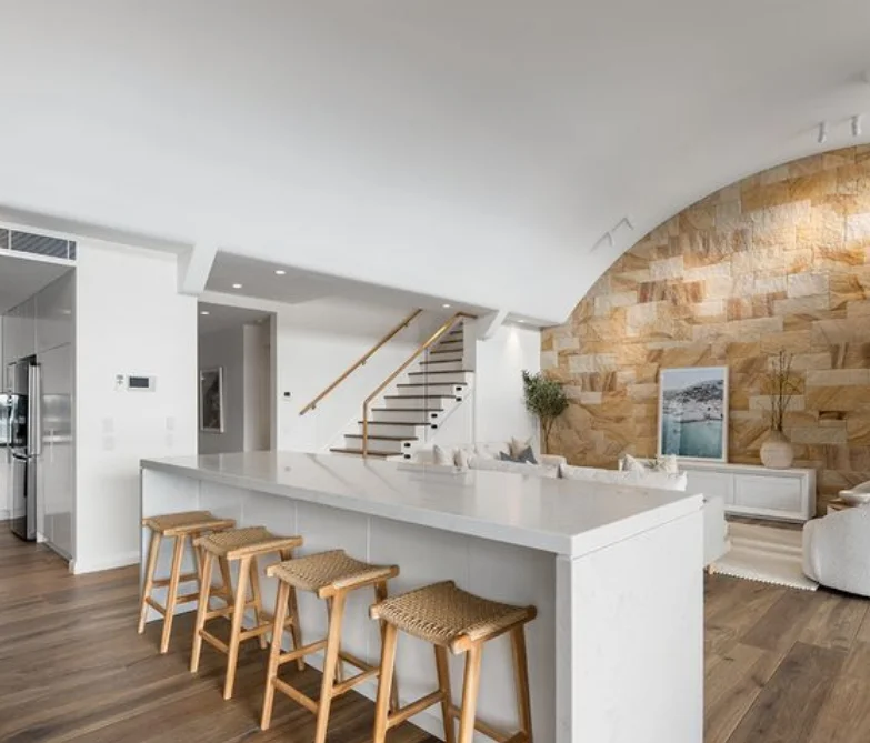 Newport home modern kitchen with island, bar stools, and stone feature wall.